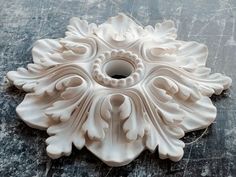 a white decorative object sitting on top of a wooden table next to a tile floor