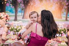 a woman holding a small child in her arms at a table filled with teddy bears