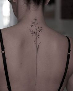 the back of a woman's neck is shown with a flower tattoo on it