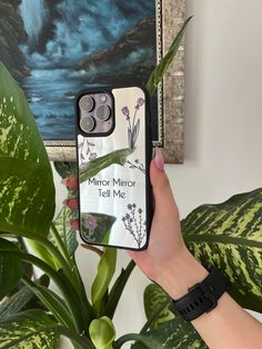 a woman holding up her phone case with the words mirror, tell me on it