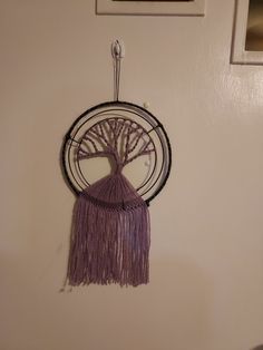 a wall hanging with a tree on it and a purple tasseled piece in the center