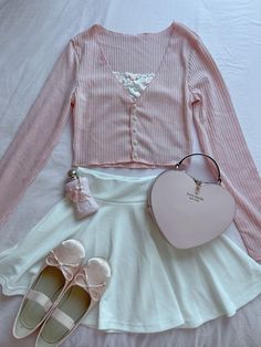 a white skirt, pink shirt and heart shaped purse are on a bed with shoes