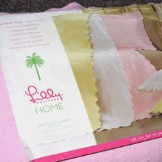 a pink and yellow bed spread with palm tree on it's side, next to a pillow