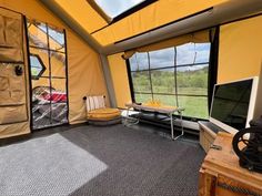 the inside of a tent with a television and couch