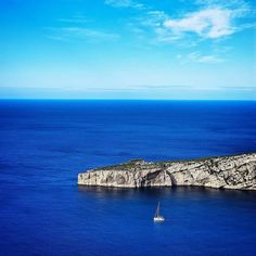 a sailboat is out on the water near an island in the middle of the ocean