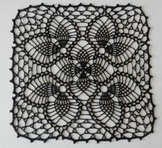 an intricate black doily on a white wall