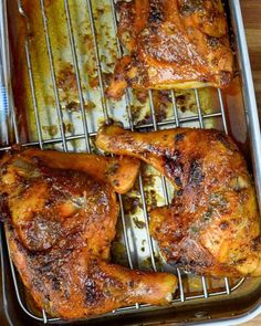 two chicken legs on a baking sheet in a roasting pan with tongs next to them