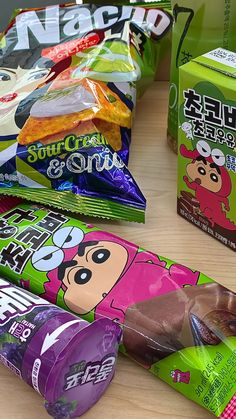 some candy bars are lined up on a table with other snacks in the back ground