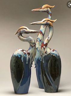 two blue vases with birds standing on top of each other in front of a gray background