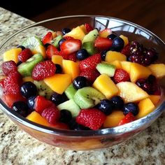 a glass bowl filled with fruit on top of a counter