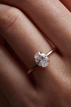 a woman's hand with a diamond ring on top of her finger, showing the center stone