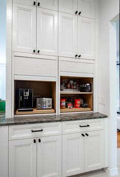 a kitchen with white cabinets and black counter tops in the center, filled with food