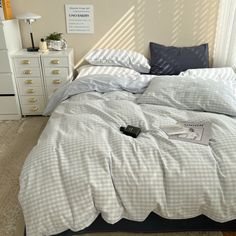 an unmade bed in a bedroom next to a dresser with drawers and a lamp