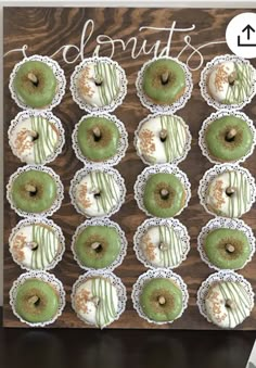 green donuts with white frosting and sprinkles are arranged on a wooden board