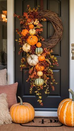 two pumpkins are sitting on the front porch with a wreath and other fall decorations