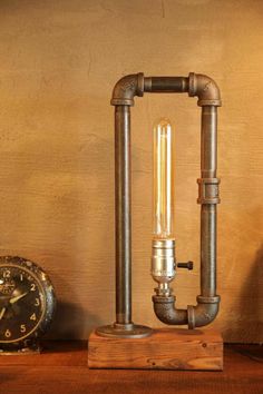 an old fashioned steam pipe lamp on a wooden table next to a small alarm clock