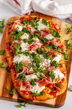 a pizza topped with cheese and veggies on top of a wooden cutting board