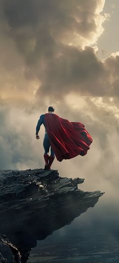 a man in a red cape standing on top of a cliff