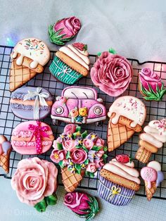 there are many different decorated cookies on the cooling rack with flowers and ice creams