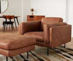 a living room with a chair and ottoman on the floor in front of a mirror