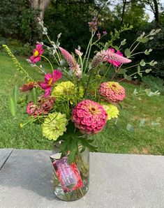 a vase filled with lots of flowers on top of a cement slab in the grass