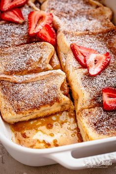 french toast with powdered sugar and strawberries in a casserole dish, ready to be eaten