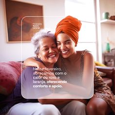 two women hugging each other on the couch in front of a window with an orange turban