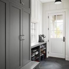 an entryway with gray cabinets and black flooring is flanked by a white door