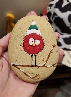 a hand holding a painted rock with a bird on it