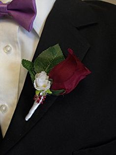 a boutonniere with a single white rose and green leaves on it's lapel