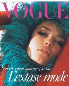 a magazine cover with a woman laying on top of a red blanket and green feathers