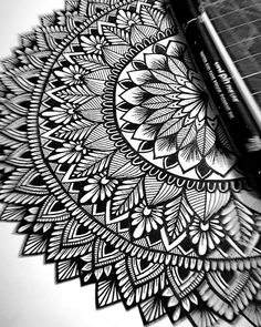 a pen is laying on top of an intricately designed piece of paper that looks like a flower