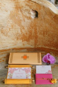 the wedding stationery is laid out next to an orchid flower on a piece of wood