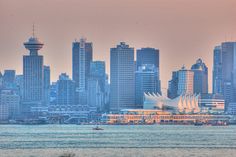 the city skyline is seen from across the water with boats on it and tall buildings in the background