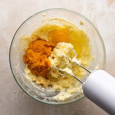 a mixing bowl with eggs, butter and other ingredients for making mashed potato casserole