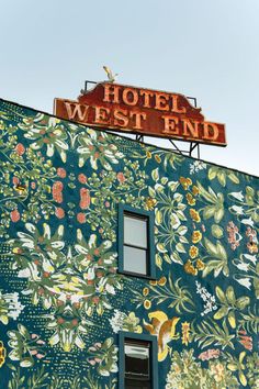 a hotel sign on top of a building with flowers and birds painted on the wall