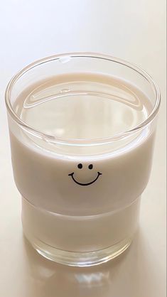 a smiley face drawn on the side of a glass cup filled with milk or water