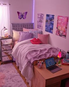 a room with a bed, desk and laptop on the table in front of it