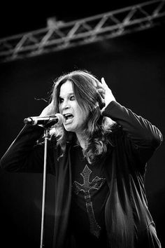 a woman with long hair holding her hands up to her head while singing into a microphone