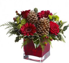 a vase filled with red flowers and pine cones