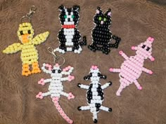 four beaded keychains are sitting on a towel, one has a cat and the other is a dog