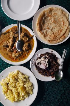 four plates with different types of food and spoons on the table next to each other