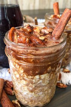 two jars filled with oatmeal sitting on top of a table next to cinnamon sticks