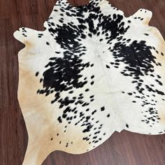 a black and white cowhide rug on a wooden floor with dark spots in the center