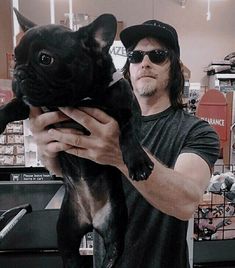 a man holding a black dog in his arms and wearing sunglasses on top of him