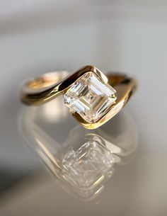 an engagement ring with a diamond in the center on a reflective surface, close up