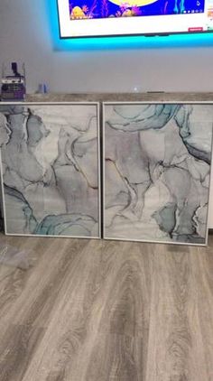 two marble sideboards in front of a tv on the wall with a blue light behind them