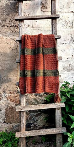 an orange and green blanket sitting on top of a wooden ladder