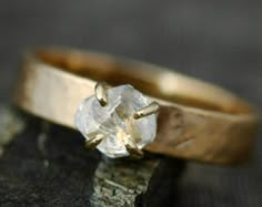 a gold ring with a white diamond on it sitting on top of a piece of wood