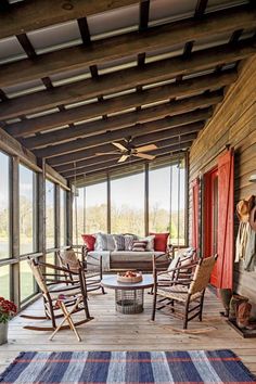 a porch with rocking chairs and a rug on the wooden floor next to it is covered in wood planks